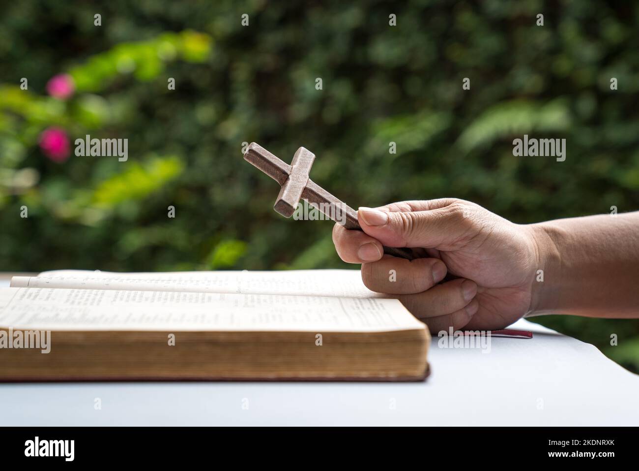 Hombre sosteniendo un crucifijo religioso de madera con una biblia abierta. Concepto de fe cristiana. Foto de stock