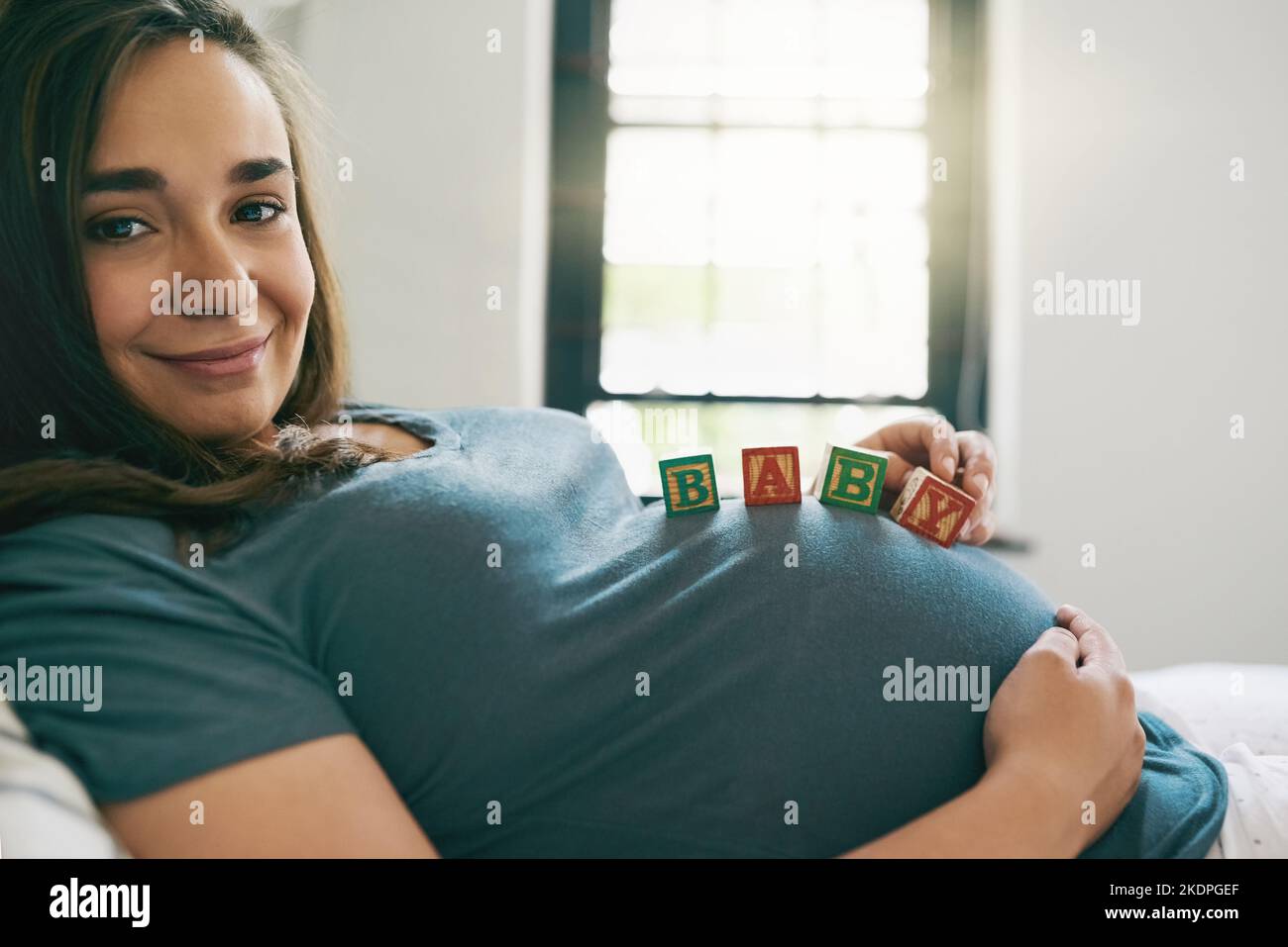 No puedo esperar para jugar con mi pequeña. Una mujer joven con el bebé se bloquea en su vientre embarazada. Foto de stock