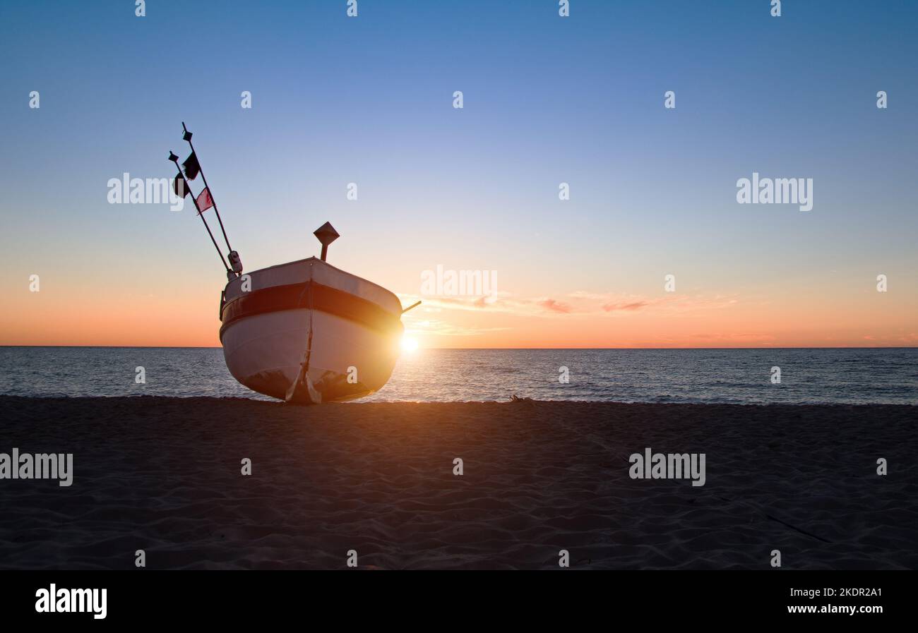 Barco de pesca en la playa de la costa polaca del Báltico cerca de Rewal. Puesta de sol Foto de stock