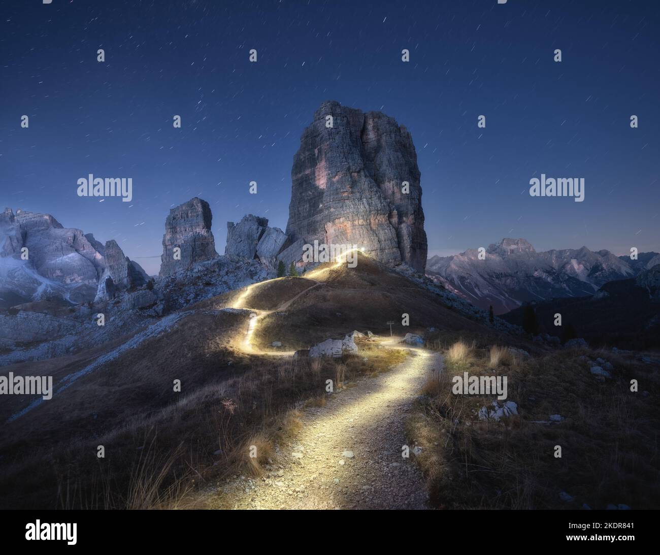 Senderos de linterna en el camino de montaña contra rocas altas por la noche Foto de stock