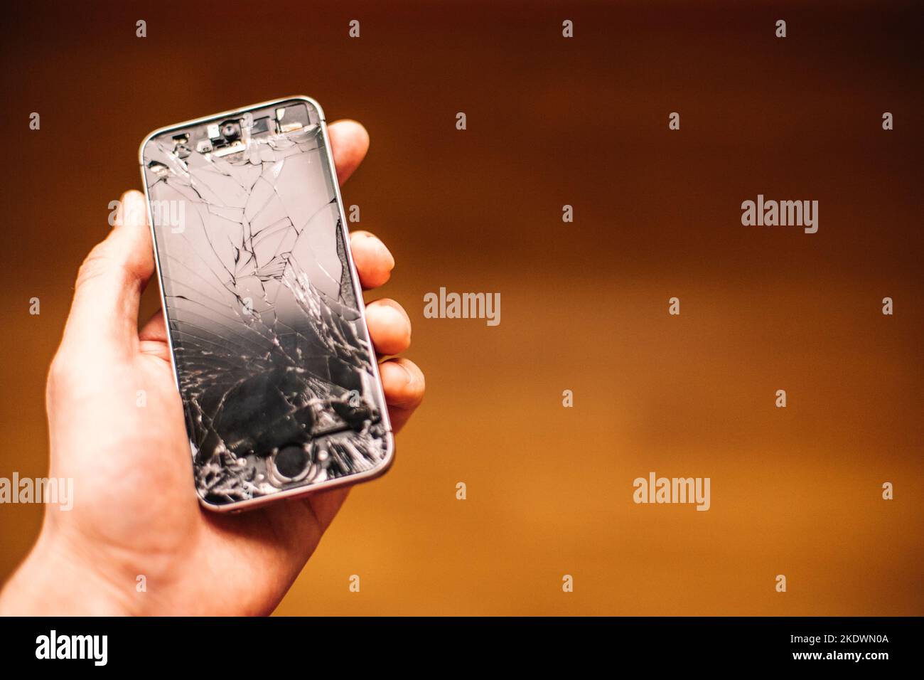 Persona que sostiene en la mano smartphone roto con la pantalla agrietada Foto de stock