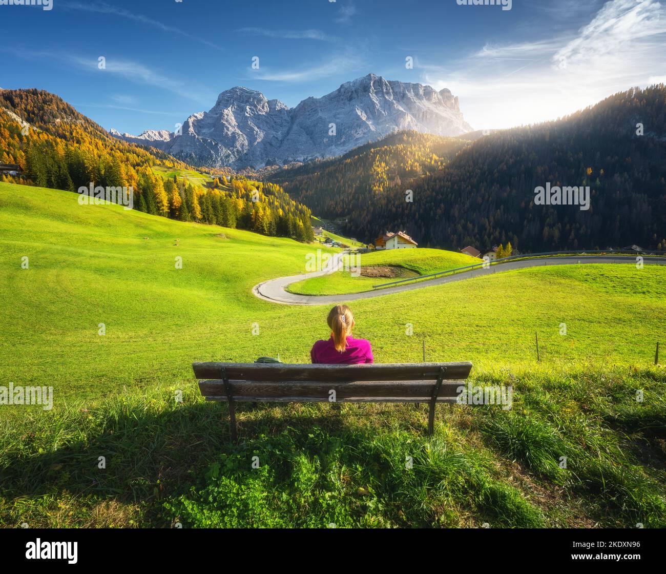Mujer joven sentada en el banco y hermoso pueblo alpino Foto de stock
