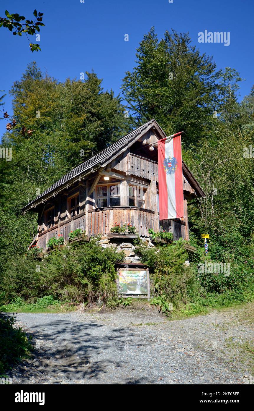 Austria, cabaña de madera con techo de madera y bandera nacional de Austria por el llamado Strutz-Mill, un antiguo molino de agua en Estiria, fue también un ganador en A. Foto de stock