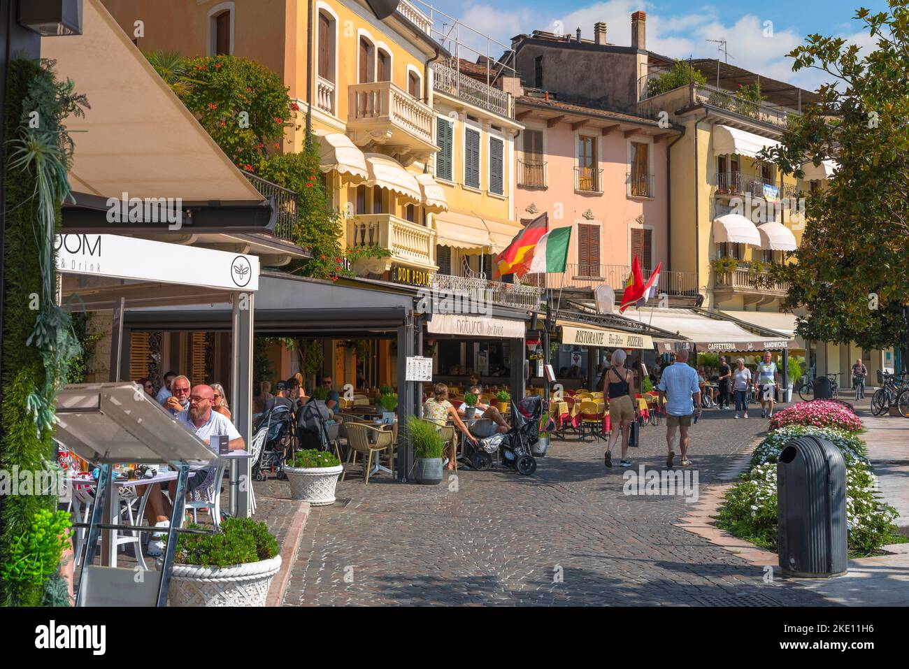 Italia comida bebida, ver en verano de las personas sentadas fuera en las mesas de restaurante en la Piazza Decorati al Valor Civile en la ciudad de Salo, Lago de Garda Foto de stock