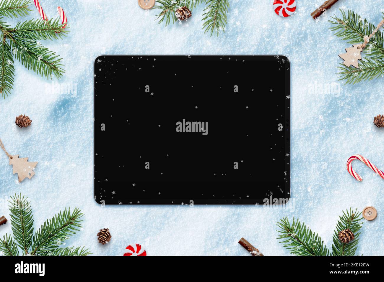 Tablet en la nieve para el diseño de aplicaciones o la promoción de copias. Rodeado de decoraciones navideñas. Vista superior, plano Foto de stock