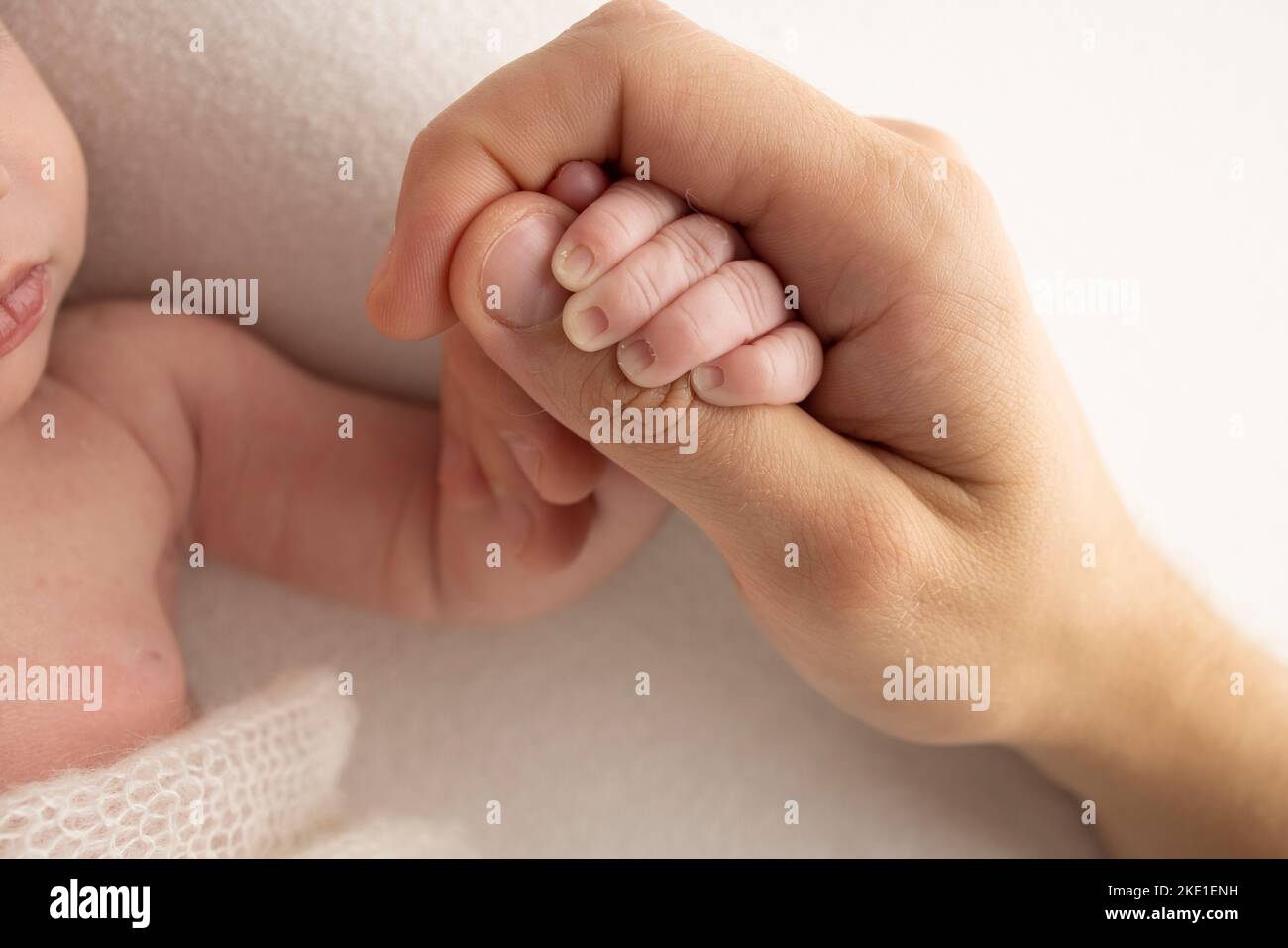 Un recién nacido se aferó al dedo de la madre, del papá. Las manos de los padres y del bebé se acercan. Foto de stock