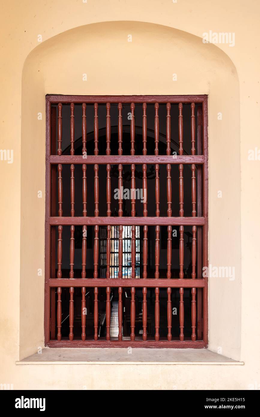 Gran ventana colonial con rejilla de madera en la fachada del edificio Foto de stock