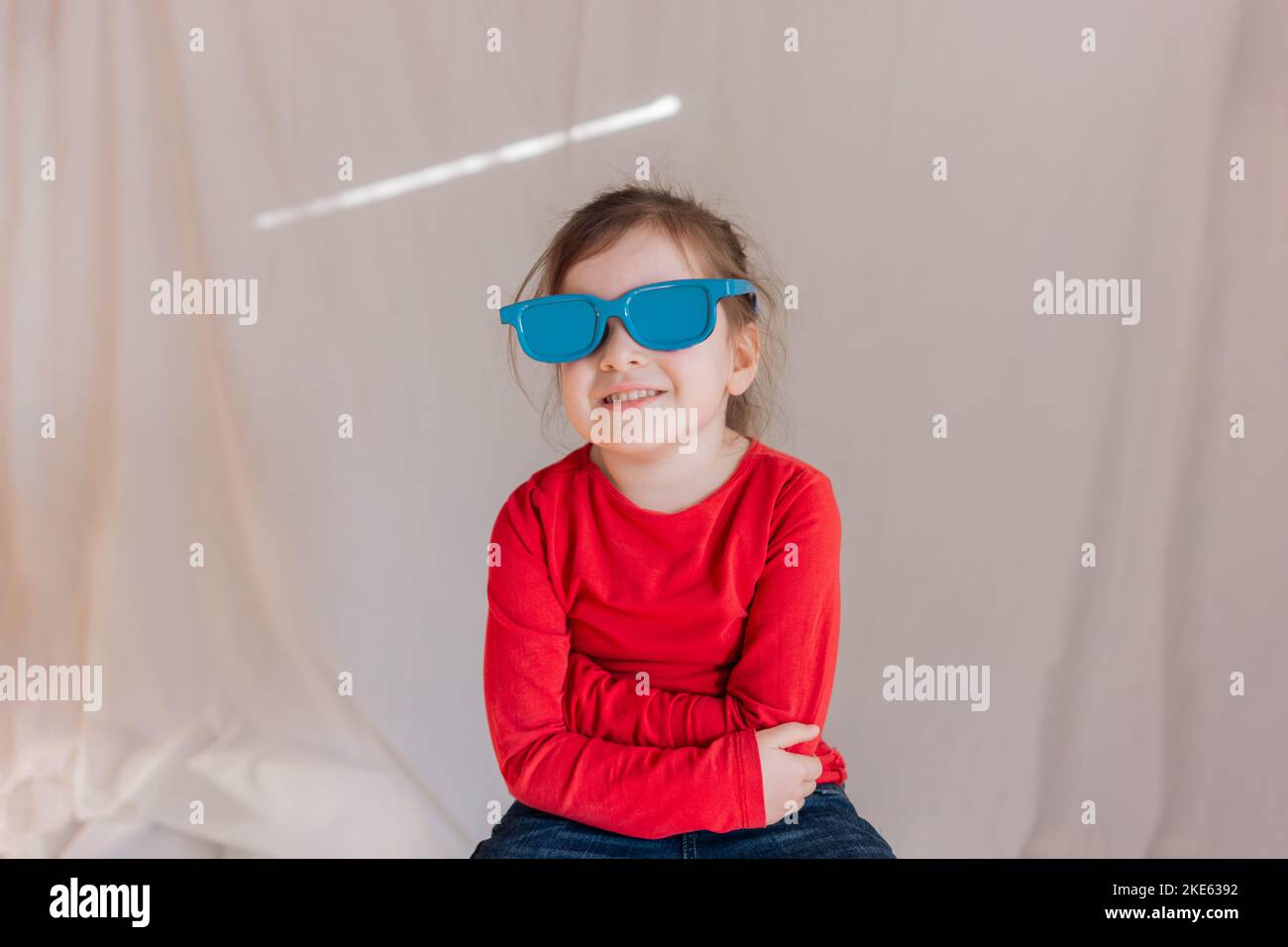 Chica feliz con gafas de sol azules sobre fondo blanco Foto de stock