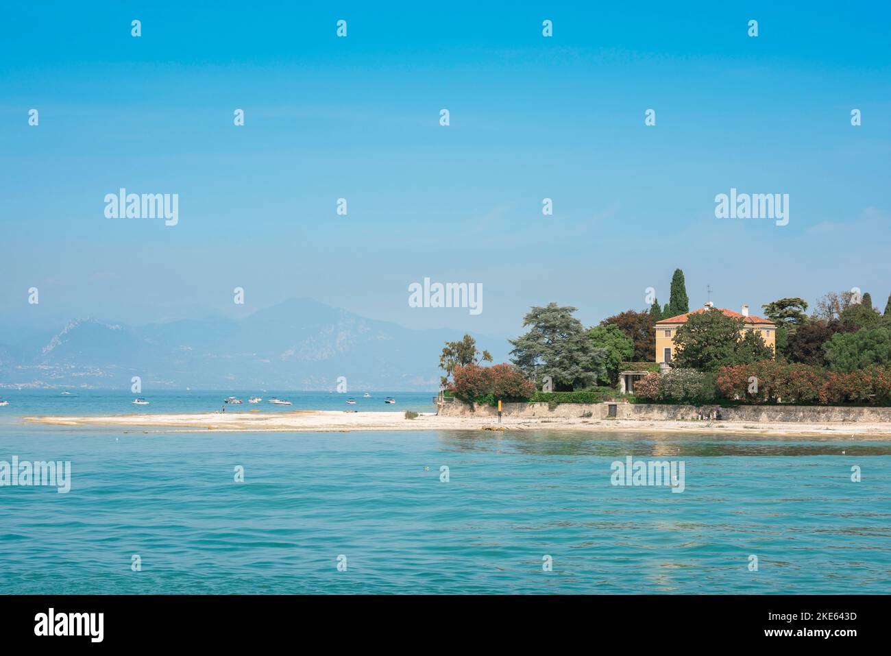 Sirmione Italia, vista en verano de la playa de arena blanca en Punta Staffalo en la pintoresca costa oeste de la península de Sirmione, Lago Garda, Italia Foto de stock