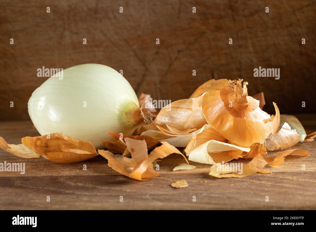 Una cebolla y mucha cáscara o piel sobre fondo de madera Foto de stock