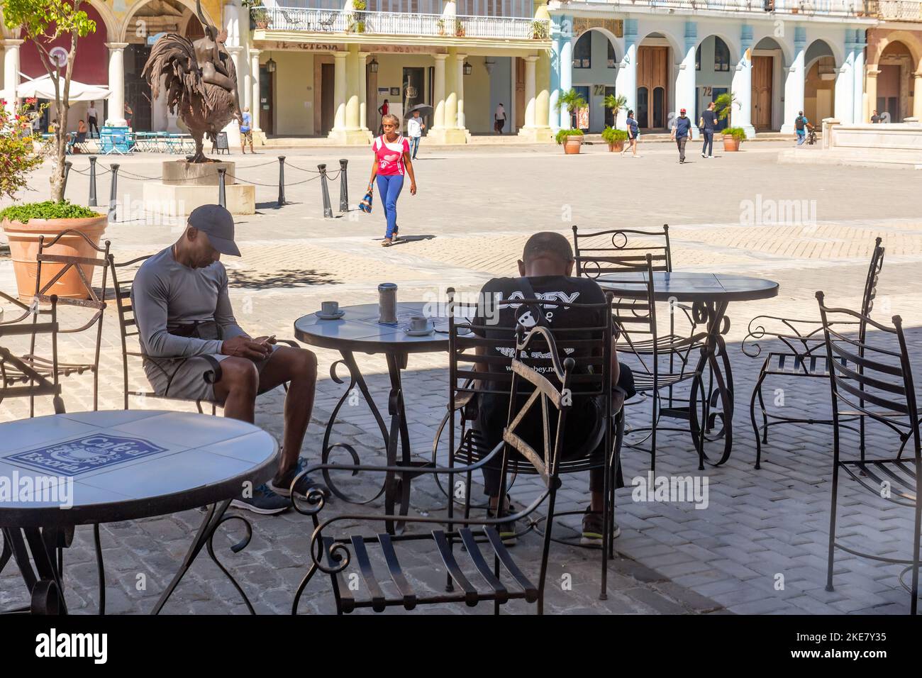 Dos cubanos se sientan en un patio vacío en Plaza Vieja. Contrariamente a lo habitual, la zona está vacía de turistas. Foto de stock
