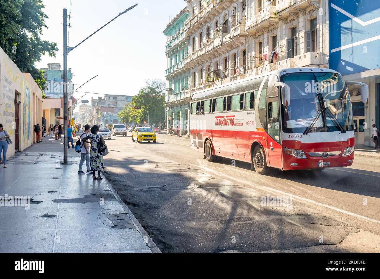 Pueblo cubano en la acera mientras un autobús Transmetro Yutong conduce en una avenida de la ciudad. Foto de stock