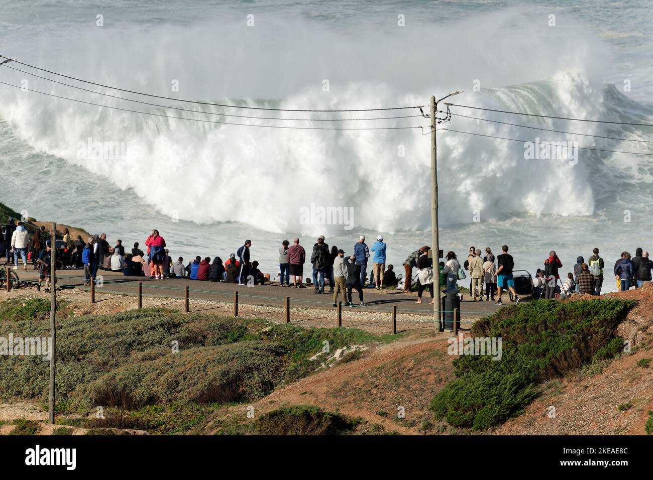 Gente viendo las grandes olas gigantes romper en Nazare, Portugal. Las