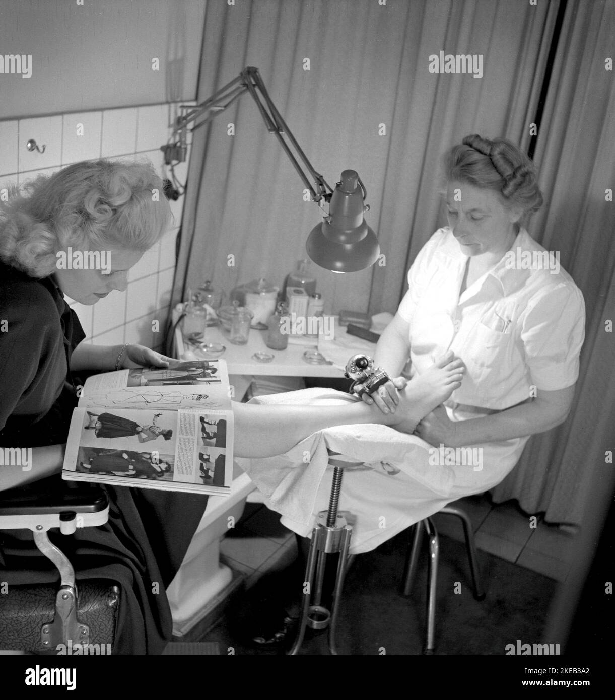 En la década de 1940s. Una mujer joven está siendo tratada y masajeada en un salón donde una mujer utiliza un dispositivo de masaje en sus pies y piernas. Suecia 1948. Conard Ref 957 Foto de stock