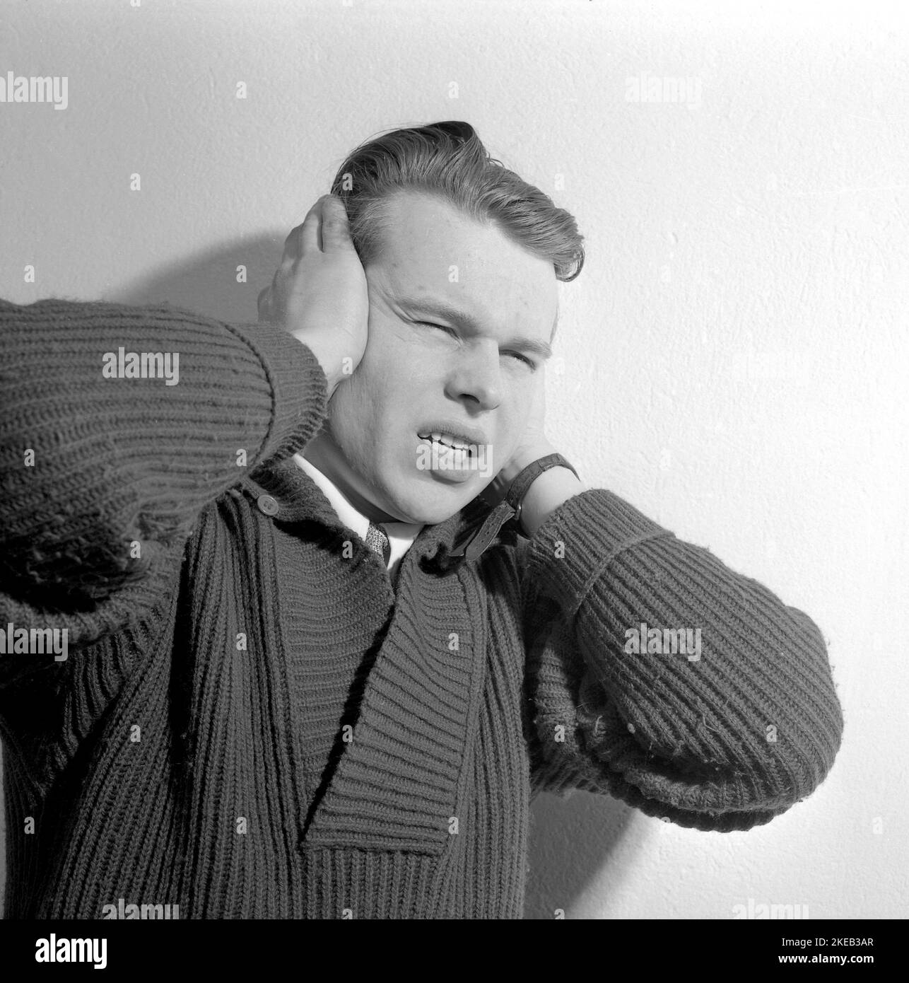 En la década de 1950s. Un joven sostiene sus manos sobre sus oídos y tiene una expresión facial que indica que puede ser sensible al sonido, trastorno auditivo, depresión, dolor de cabeza o enfermedad psiciátrica. Suecia 1956. Conard ref 3190 Foto de stock