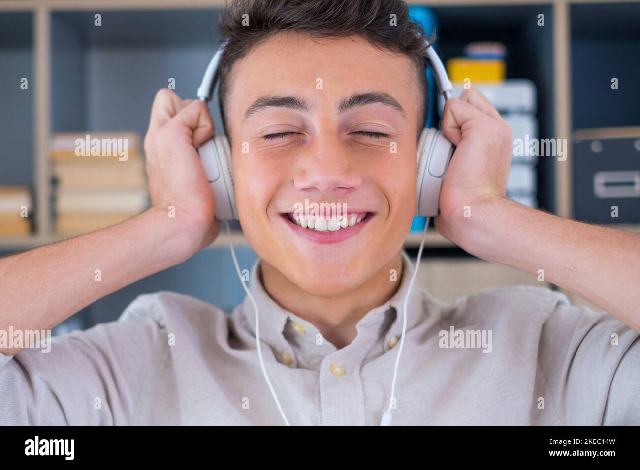 Tranquilo joven adolescente sin preocupaciones en casa, con modernos auriculares inalámbricos, escuchando su música clásica en línea y sintiéndose tranquilo y atento solo en el salón. Foto de stock