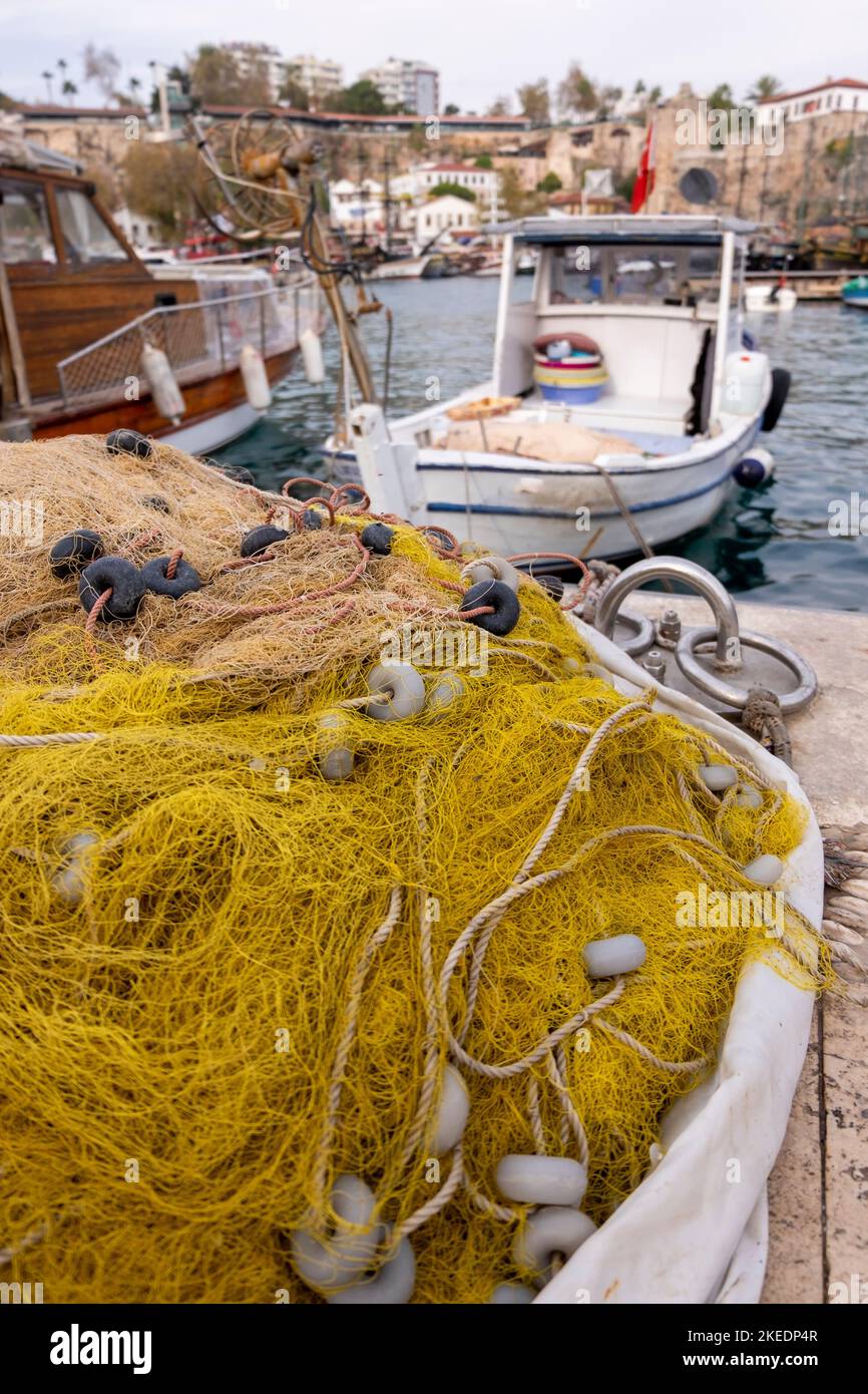 Una foto vertical de redes de pesca en el muelle del puerto y barcos de  pesca atracados en el fondo Fotografía de stock - Alamy