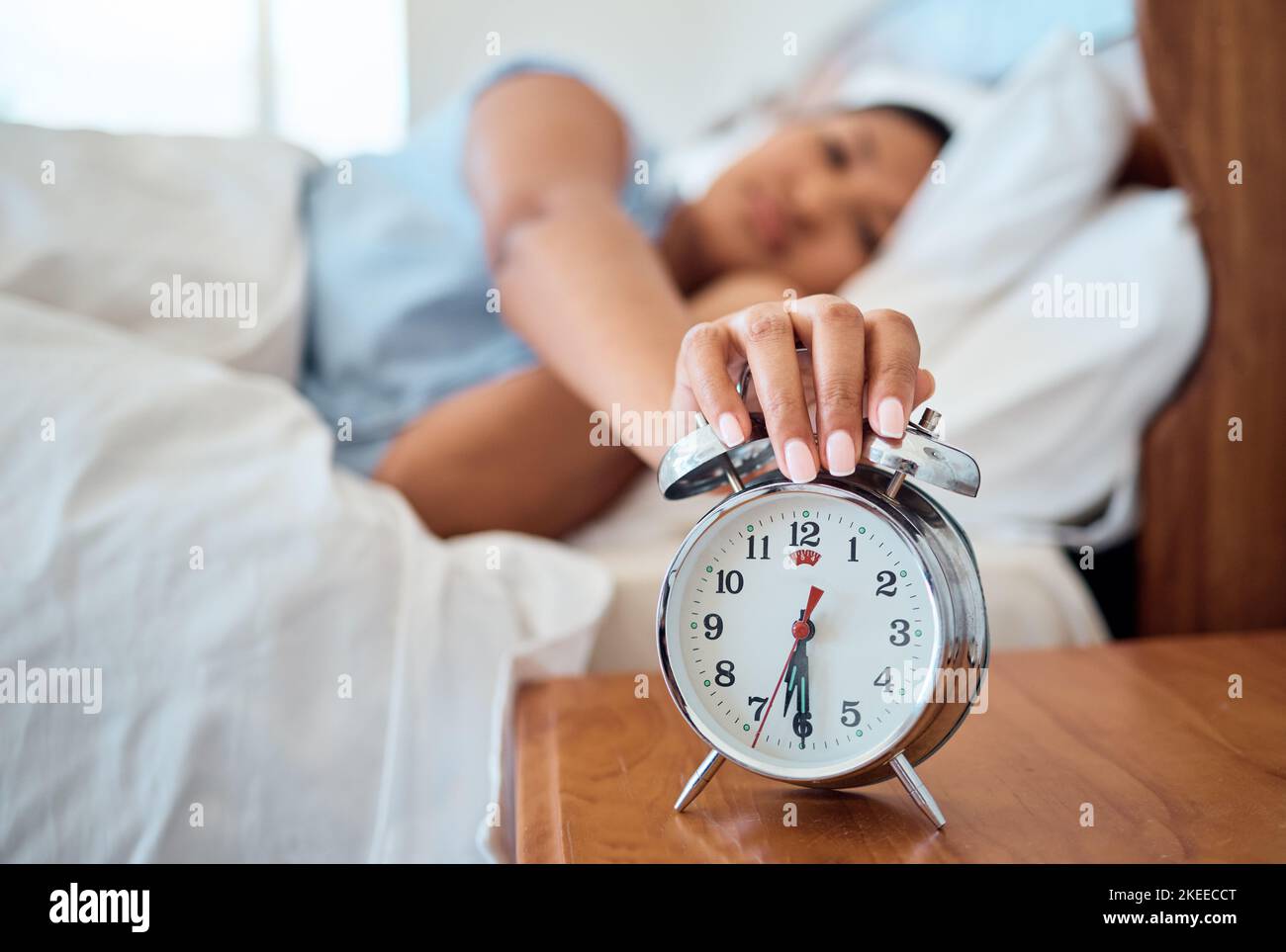 Reloj despertador, dormitorio y mujer detener la hora para despertarse desde la mañana temprano dormir en casa, casa y apartamento. Mujer cansada, alarma, ruido Foto de stock