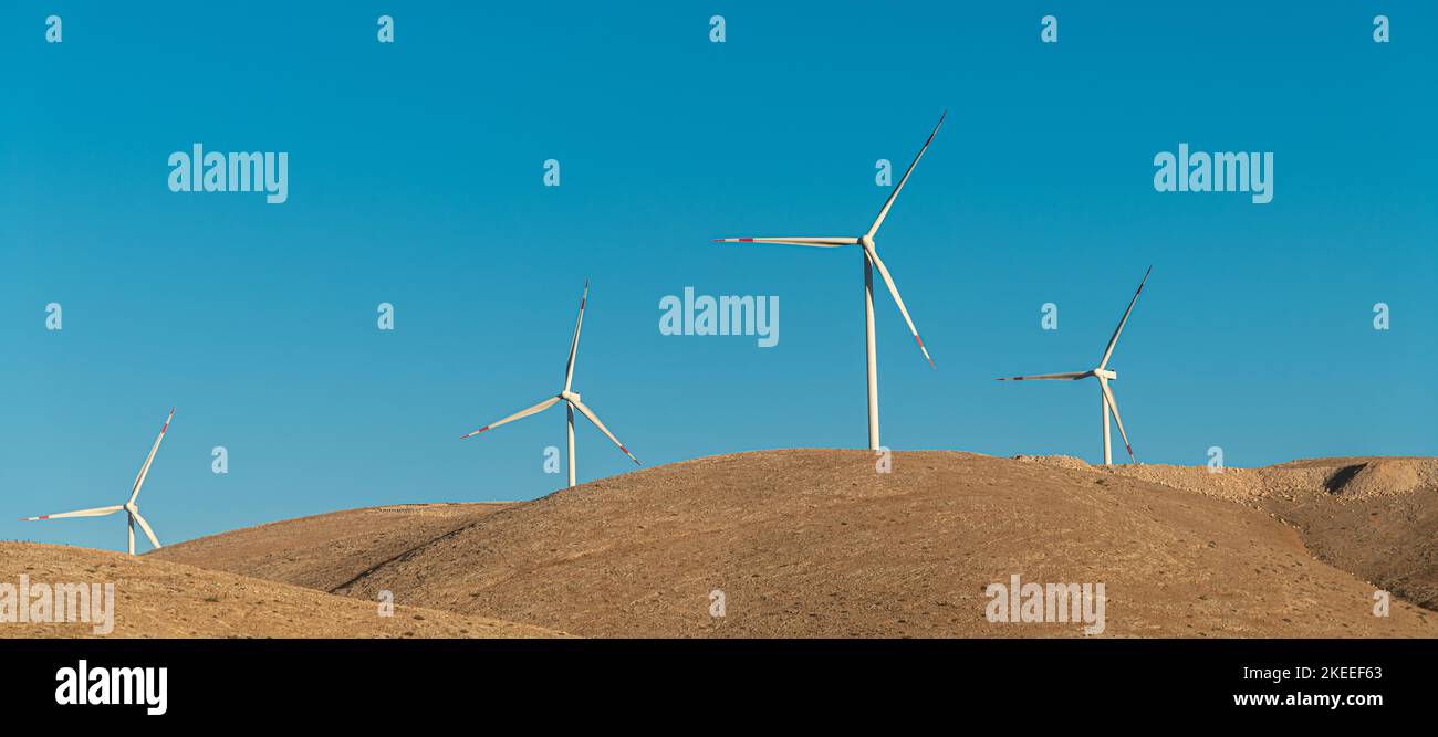 Varios aerogeneradores parados en una colina al amanecer y generando electricidad Foto de stock