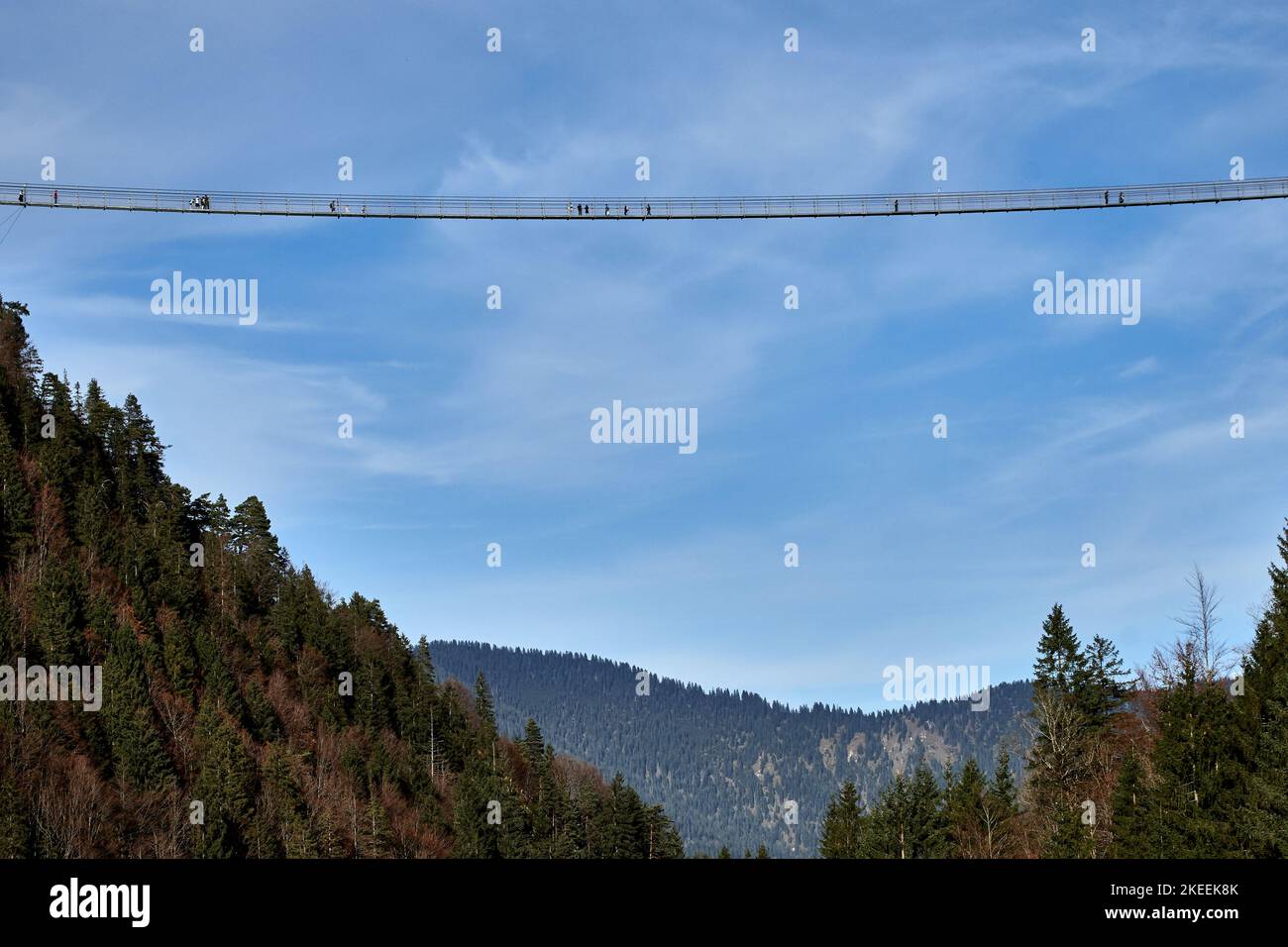 Turistas atrevidos caminando a través del puente colgante Highline179 con fondo azul cielo en Reutte, Tirol, Austria Foto de stock