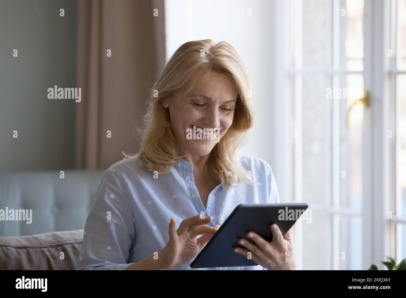Atractiva mujer madura que compra bienes o servicios utiliza la tableta digital Foto de stock