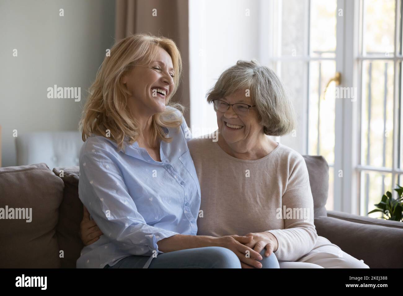 La mujer de mediana edad que se ríe disfruta hablando con una madre mayor Foto de stock