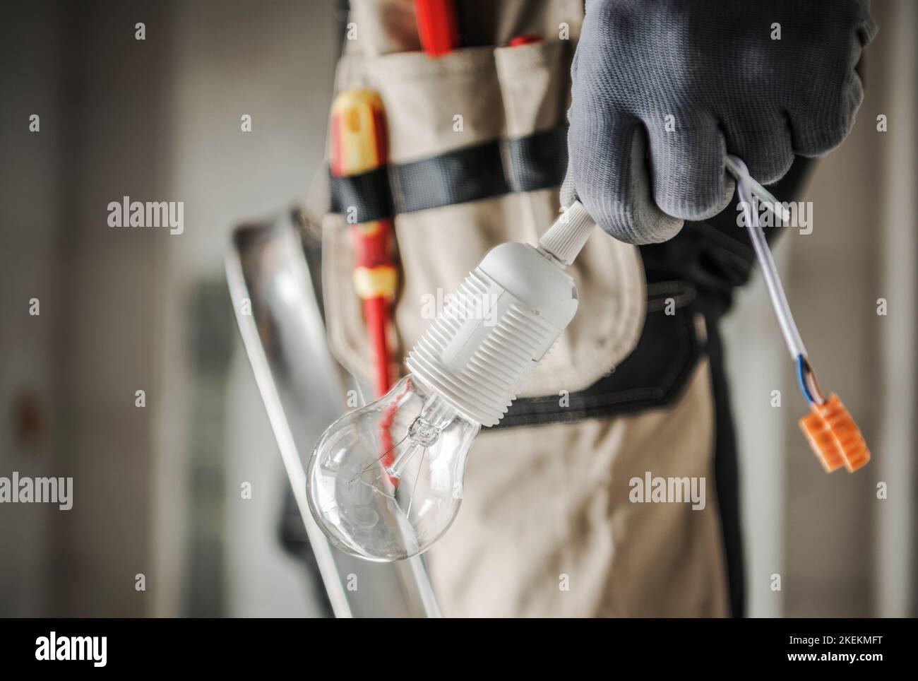 Trabajador eléctrico con bulbo en la mano preparándose para una Instalación de Punto de Luz. Primer plano foto. Concepto industrial. Foto de stock