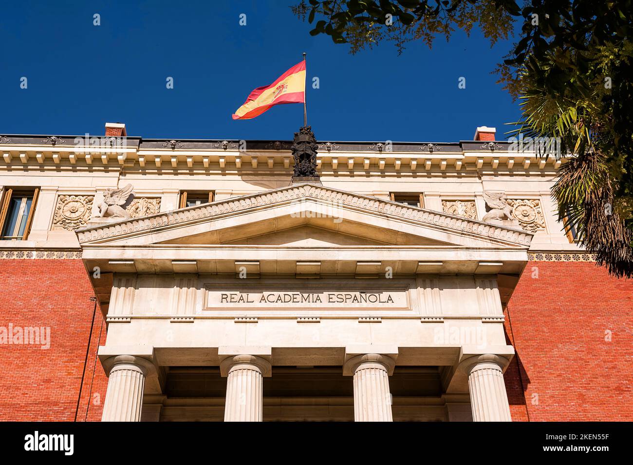 Detalle del tímpano en el edificio de la Real Academia Española (RAE) con bandera en la parte superior Foto de stock