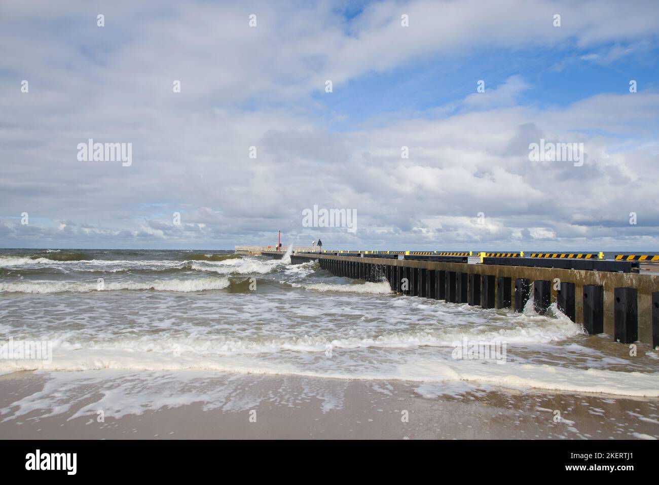 Gente de pie cerca del muelle de Niechorze y disfrutando de las olas rompientes del tormentoso mar Báltico Foto de stock
