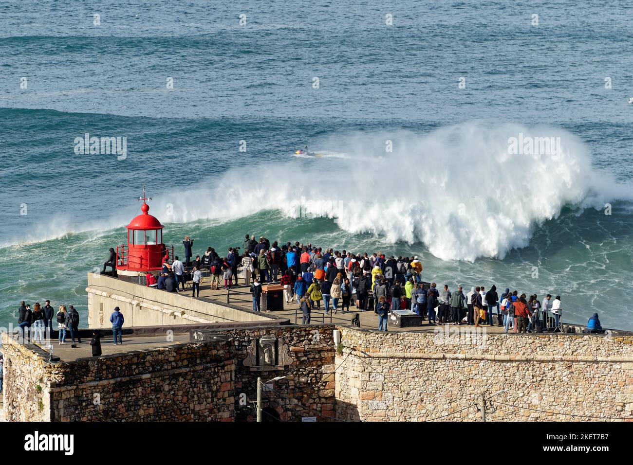 Gente observando las grandes olas gigantes rompiendo cerca del faro de