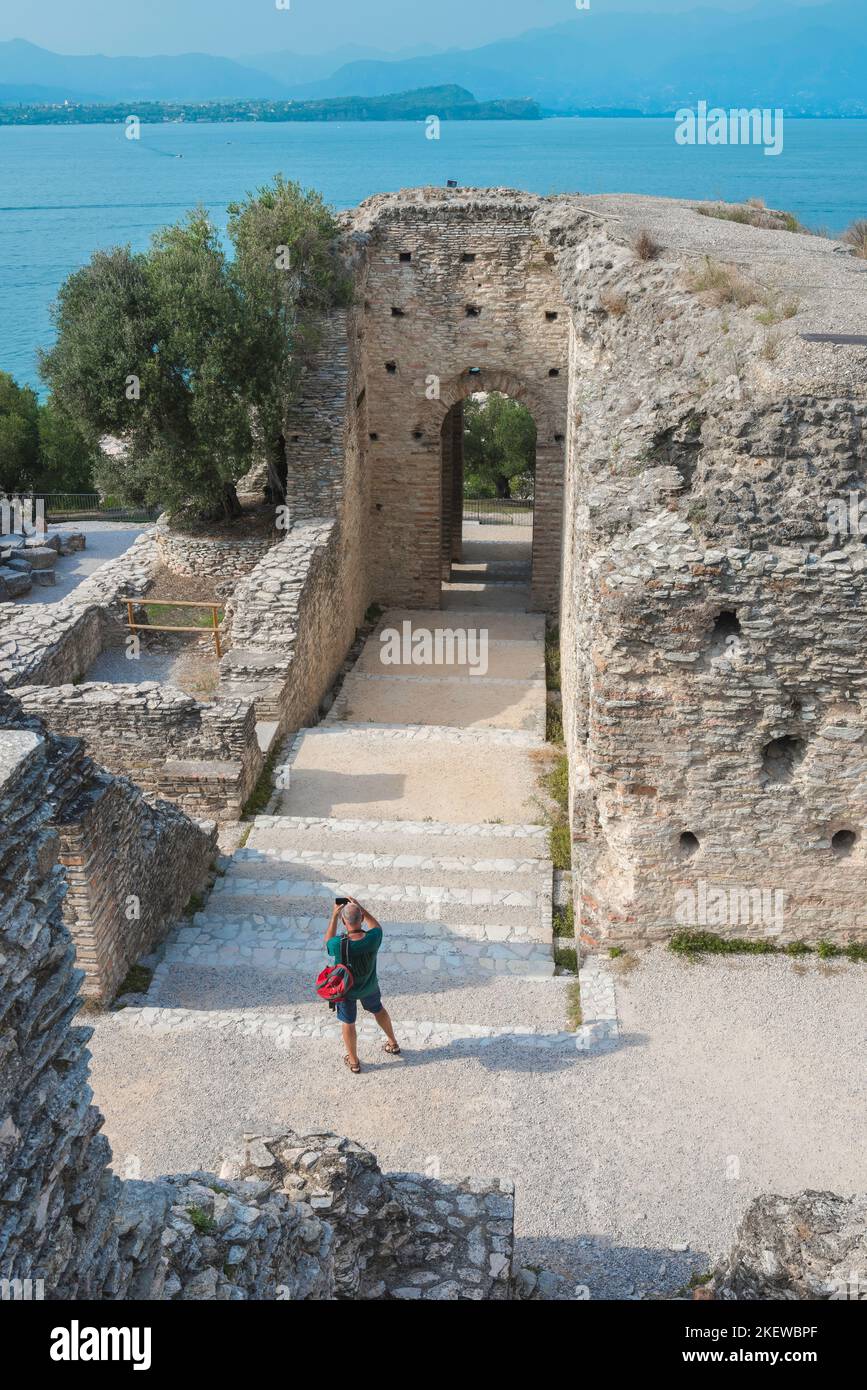 Sirmione Grotte di Catullo, vista de un turista fotografiando las ruinas de una antigua villa romana que se cree que fue la casa de Catullo, en el lago Garda Italia Foto de stock