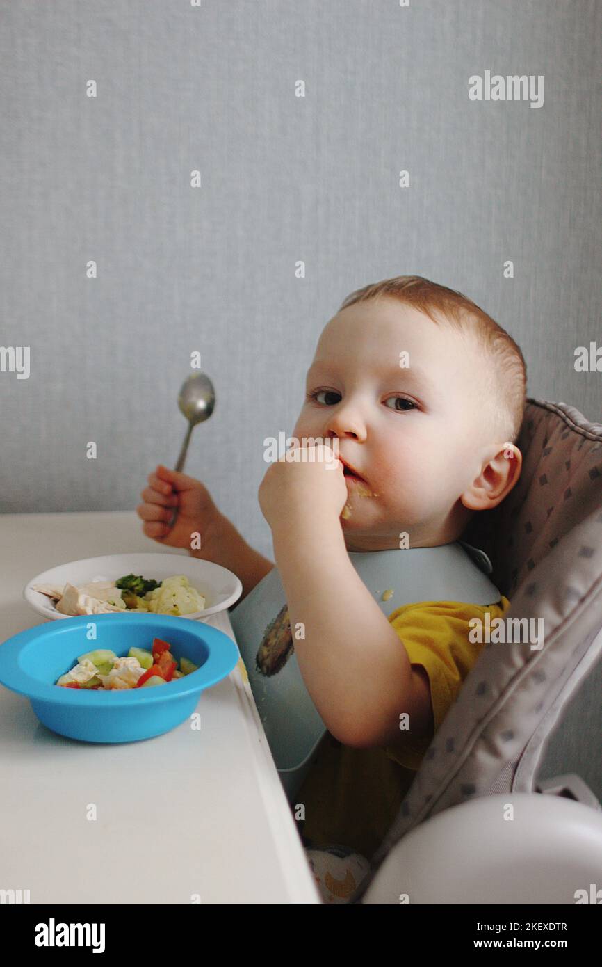 Niño sosteniendo cuchara comiendo verduras Foto de stock
