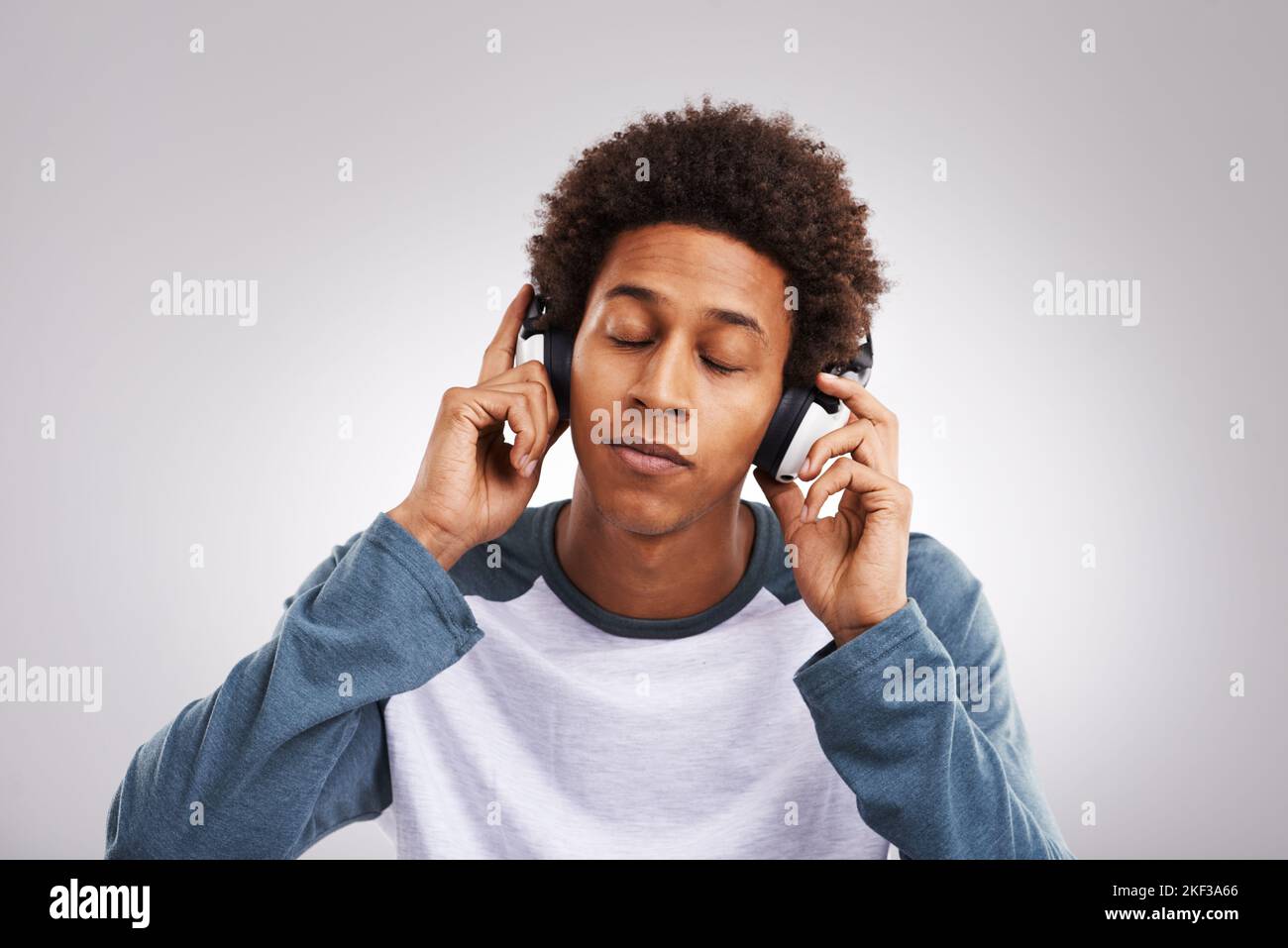 Bajo la influencia de la buena música. Estudio de un joven escuchando música con sus auriculares sobre un fondo gris. Foto de stock