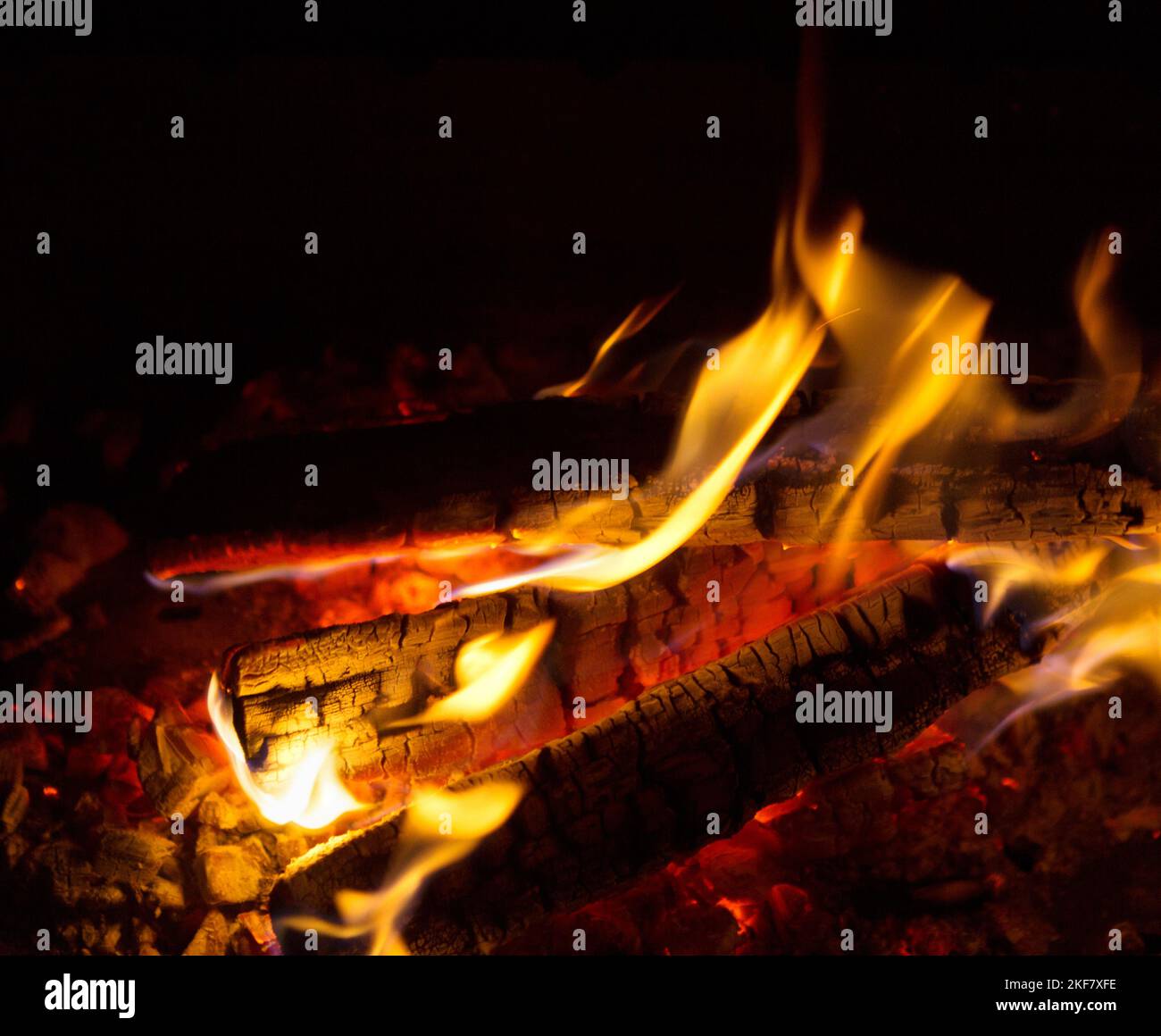 Madera quemada de cerca. Las brasas carbonizadas en una llama de fuego. Foto de stock