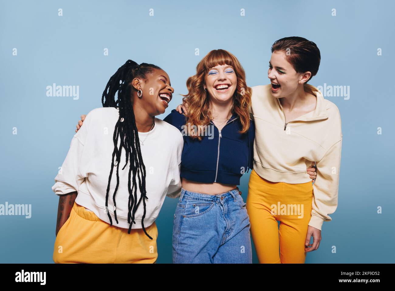 Mujeres jóvenes felices riendo juntas en un estudio. Grupo de amigas que se divierten mientras están juntas. Foto de stock