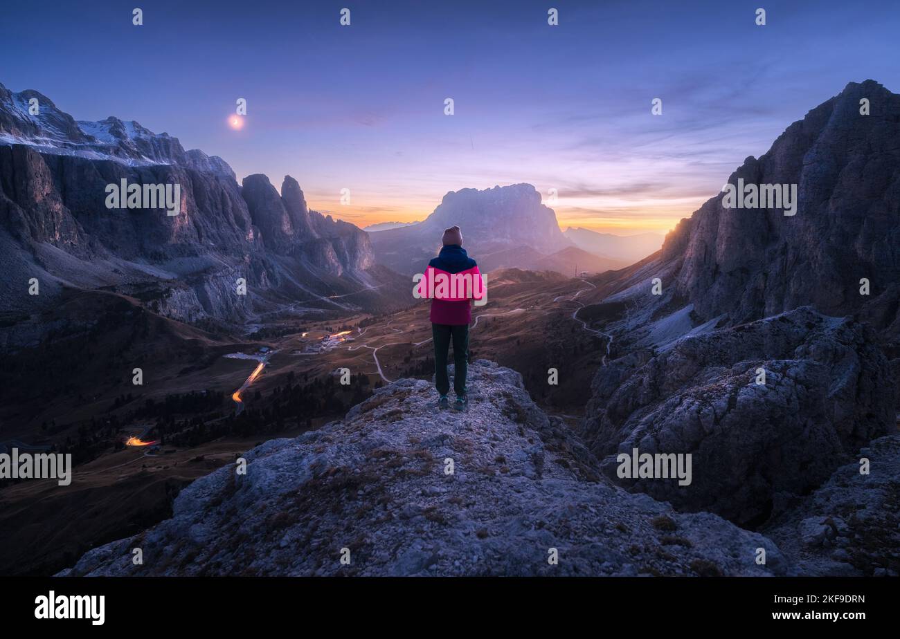 Mujer en la roca y los picos montañosos en la noche en otoño Foto de stock