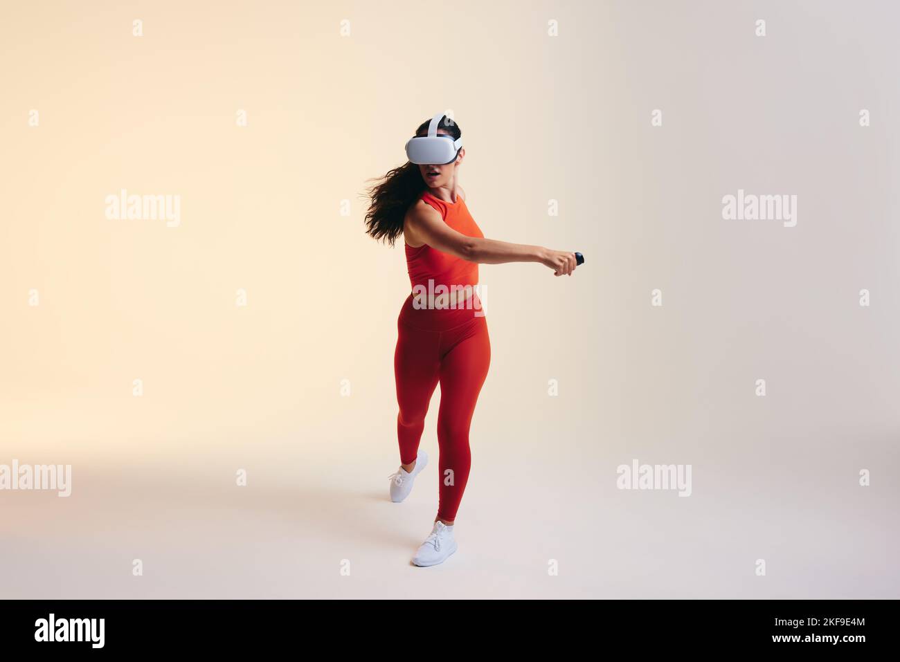 Mujer joven haciendo ejercicio con tecnología 3D. Mujer joven atlética explorando un juego virtual de la aptitud de la realidad. Mujer joven deportiva con realidad virtual Foto de stock