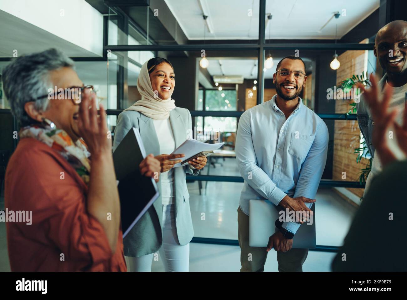 Compañeros de negocios alegres riendo felices durante una reunión de personal en una oficina moderna. Grupo de empresarios exitosos que trabajan como equipo en un mul Foto de stock