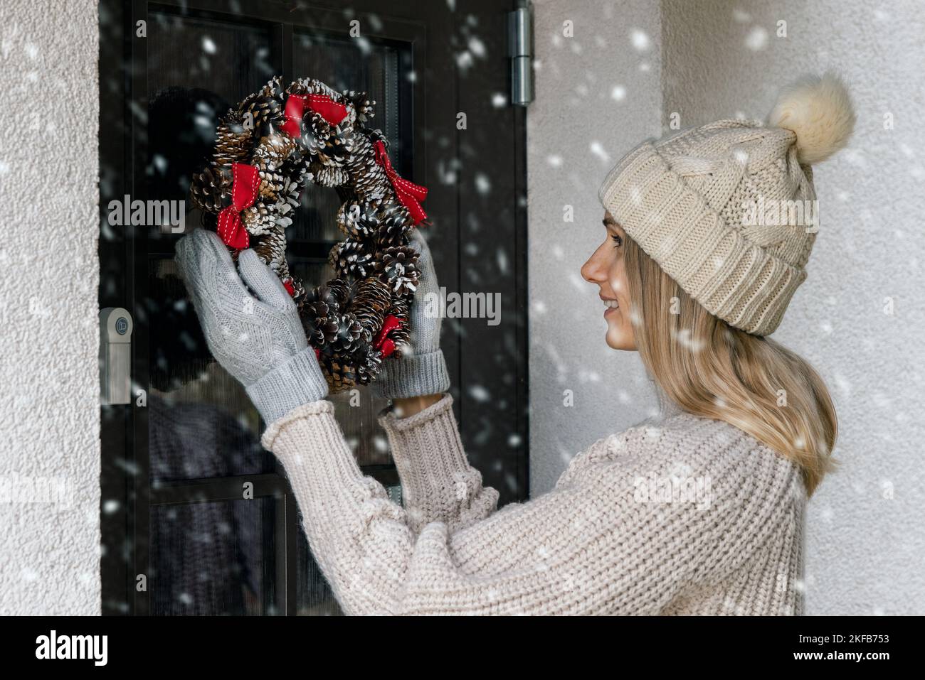 mujer cuelga una corona de navidad de adviento en una puerta de la casa. decoración del hogar Foto de stock