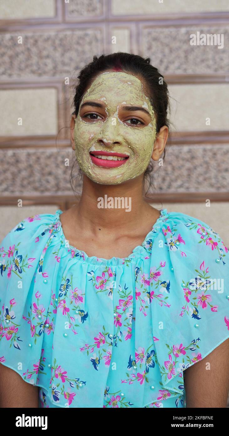 Hermosa mujer joven con máscara facial casera en la cara y relajarse en casa. Las mujeres asiáticas con Multani Mitti y Rose Water cara pack. Retrato de sp Foto de stock