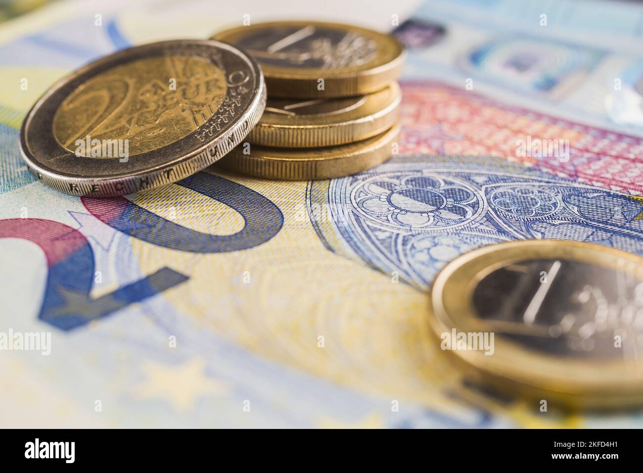 Pila de dos monedas y un euro encima de un billete de banco en papel moneda de veinte euros. Foto de stock