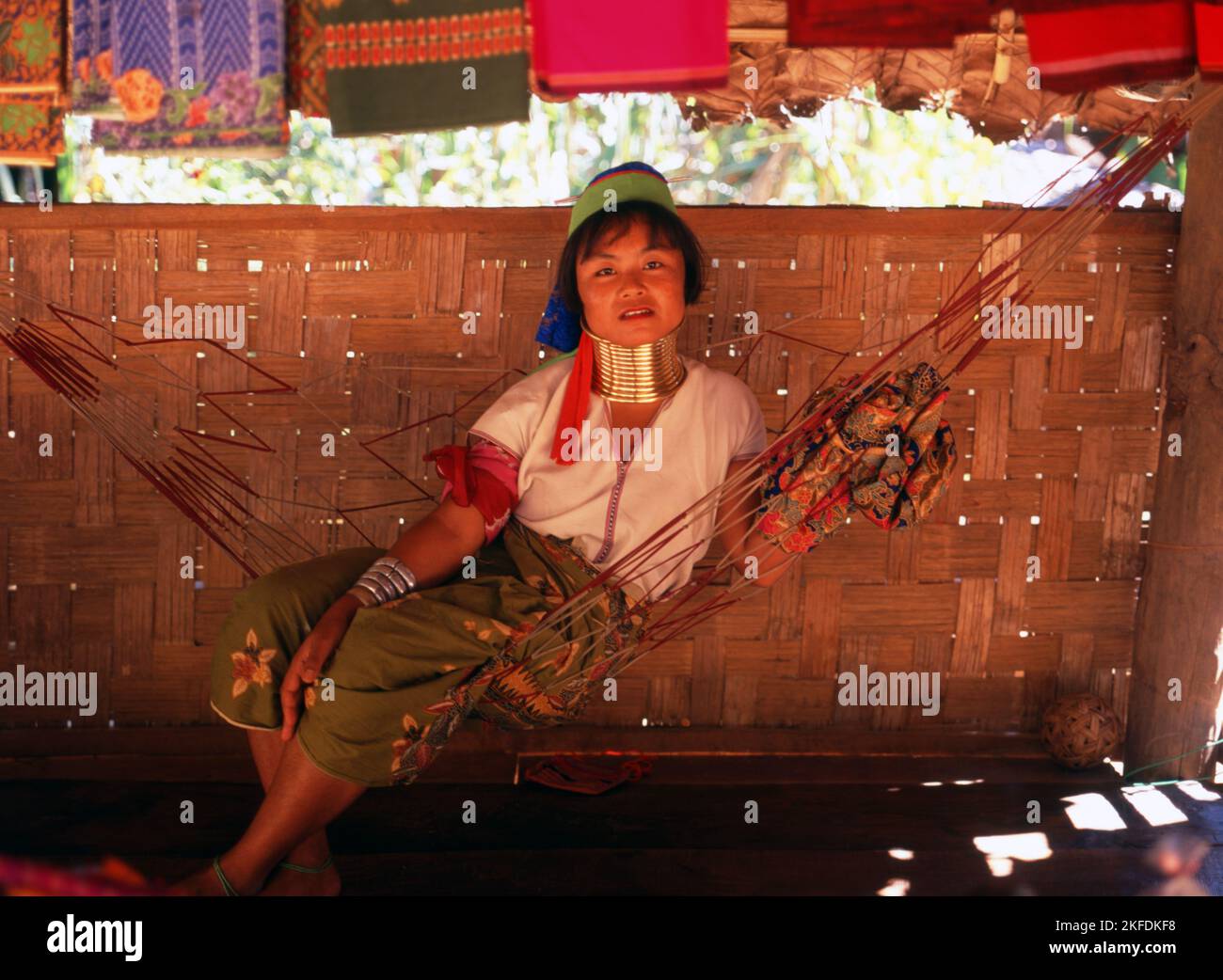 Tailandia: Una mujer Padaung (Karen de cuello largo) descansa en una hamaca, en la aldea de Padaung cerca de Mae Hong Son. Los Padaung o Kayan Lahwi o Karen de cuello largo son un subgrupo de los Kayan, una mezcla de Lawi, Kayan y varias otras tribus. Kayan es un subgrupo de la población Karen Roja (Karenni), una minoría étnica Tibeto-Burman de Birmania (Myanmar). Foto de stock
