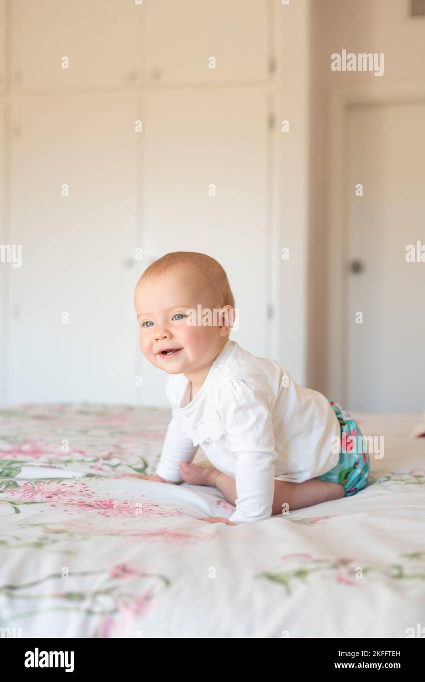 Una niña feliz que aprende a sentarse. Ella está usando un pañal de tela moderno y reutilizable. Foto de stock