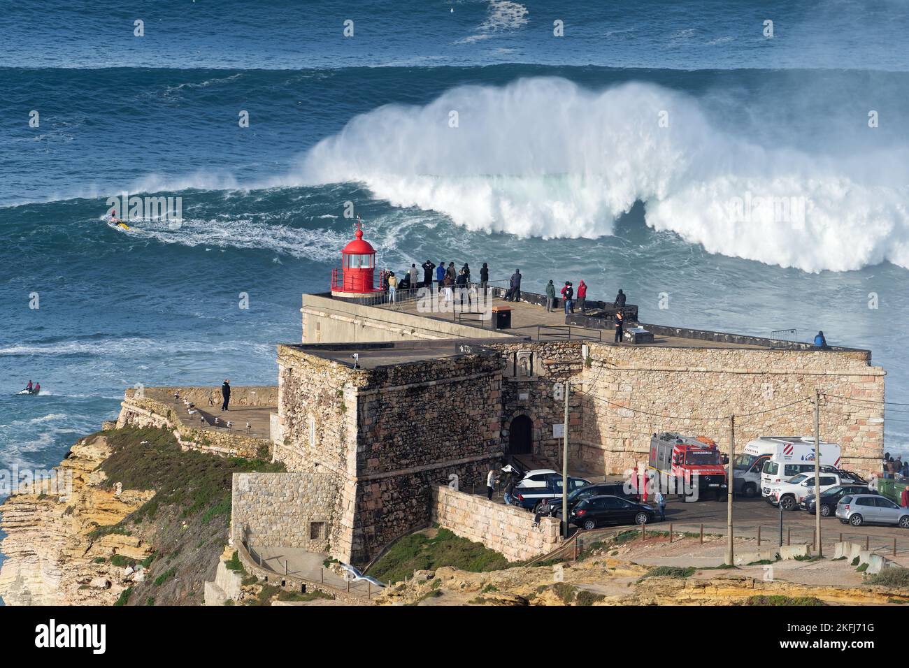Gente observando las grandes olas gigantes rompiendo cerca del faro de