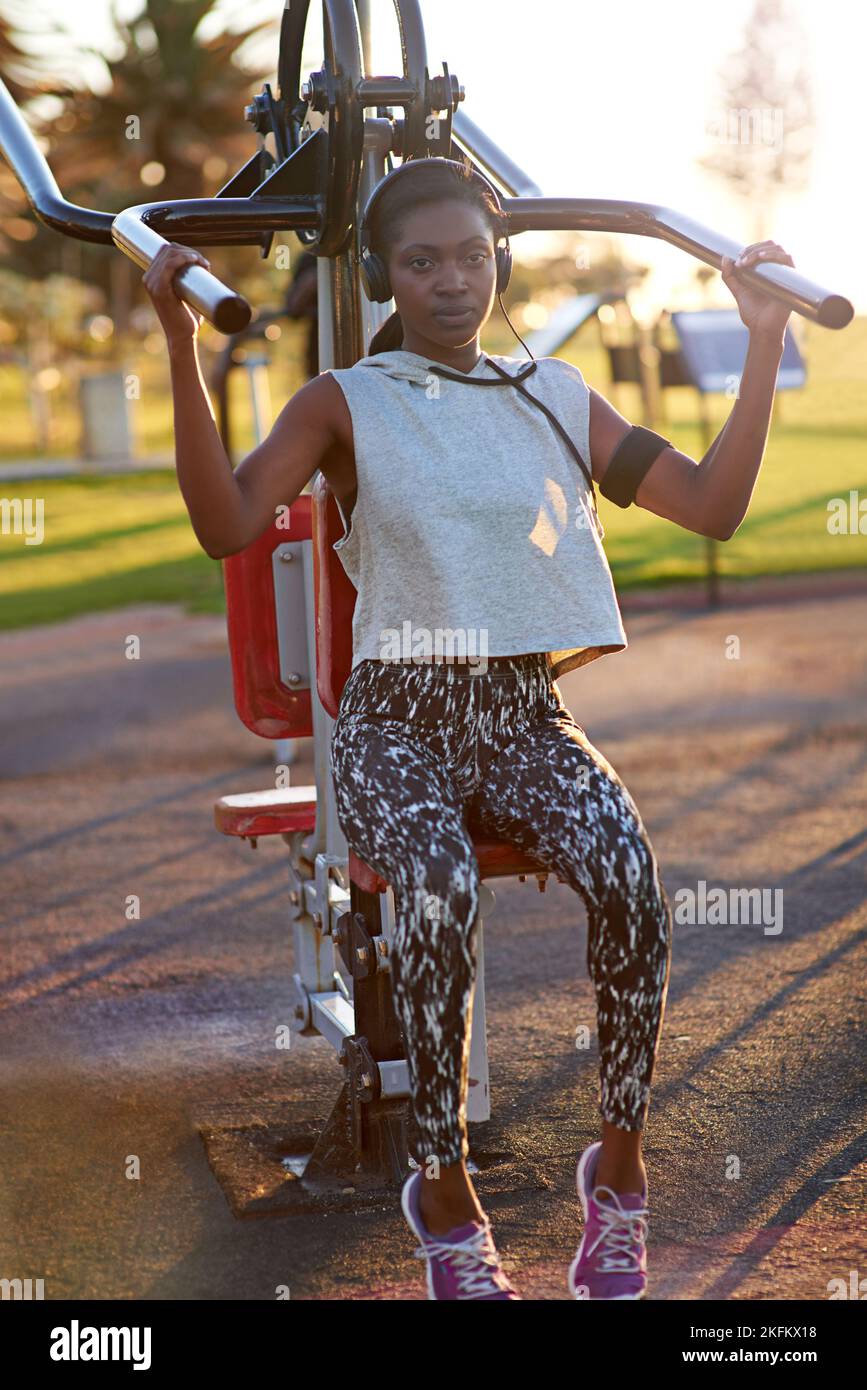 Uso del equipo de gimnasio al aire libre. Una mujer joven que usa el equipo de ejercicios al aire libre en el parque. Foto de stock