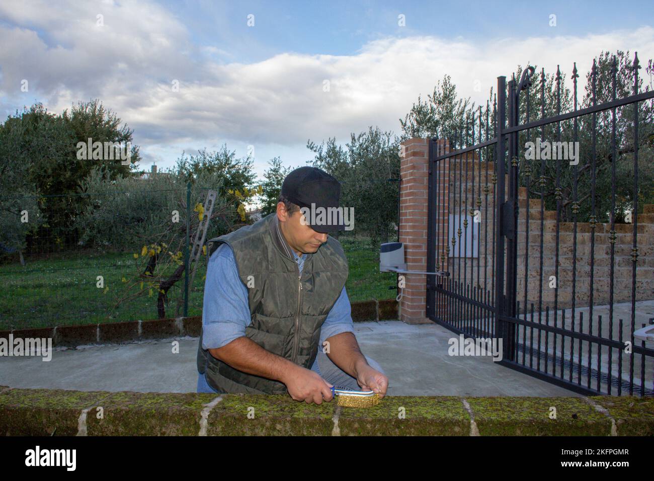 Imagen de un handyman que utiliza un cepillo de acero para eliminar la humedad y el moho de una pared de la casa. Soluciones al problema del molde y aplicación anti-molde Foto de stock