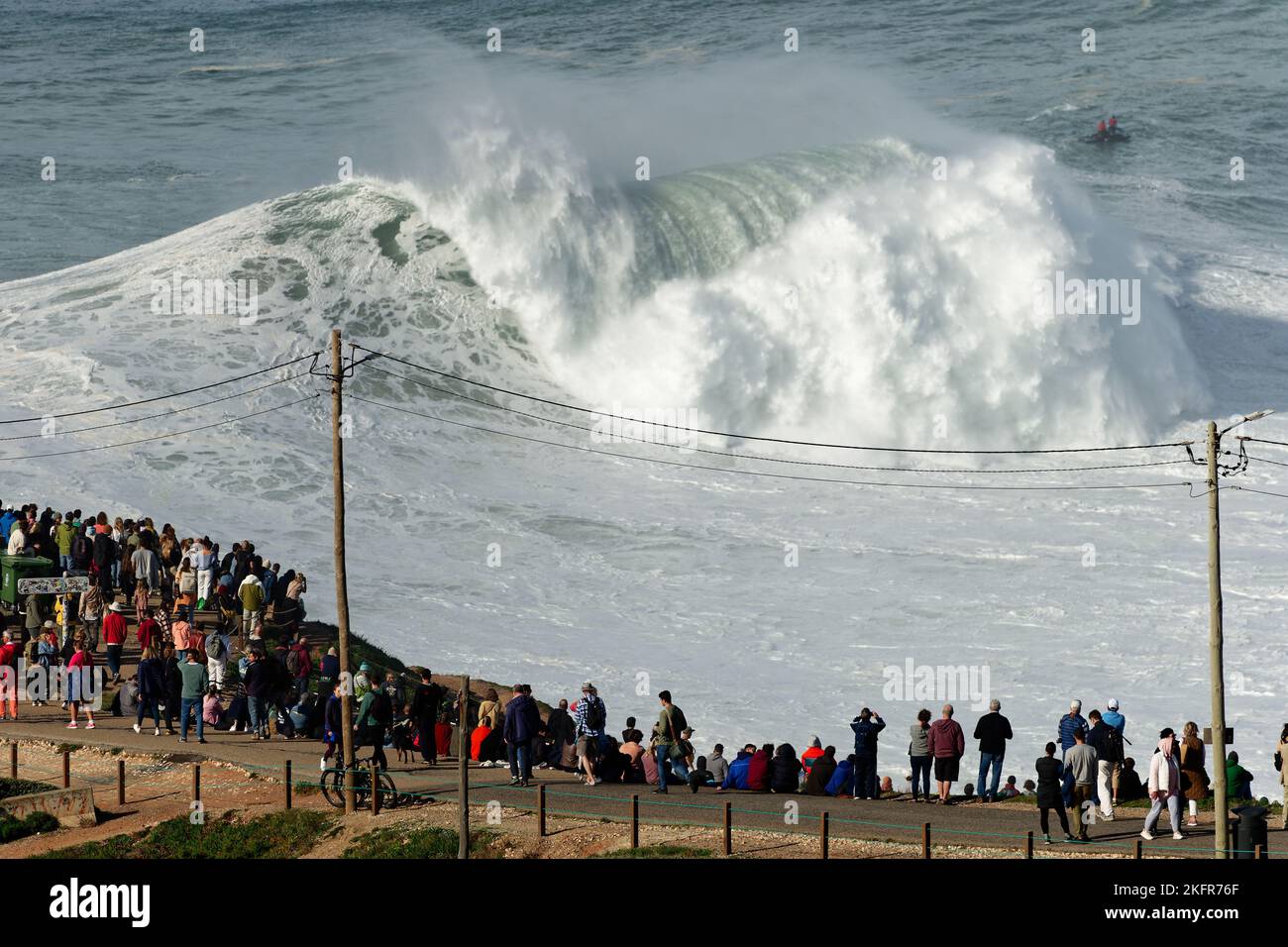Gente viendo las grandes olas gigantes romper en Nazare, Portugal. Las
