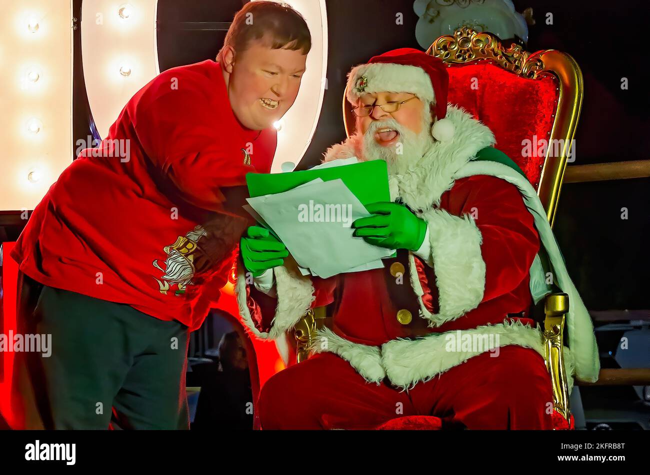 Un joven adulto repasa su lista de Navidad con Santa Claus durante la iluminación de árboles de Navidad de la ciudad, 18 de noviembre de 2022, en Mobile, Alabama. Foto de stock