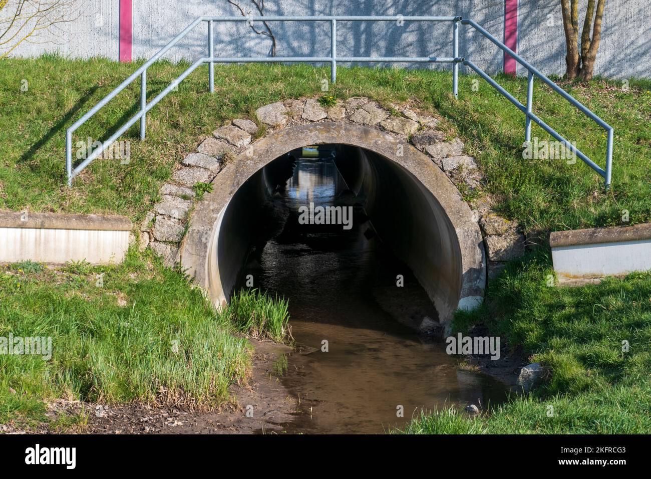 Abwasserkanal, Tunnel mit Spiegelung und Licht am Ende Foto de stock