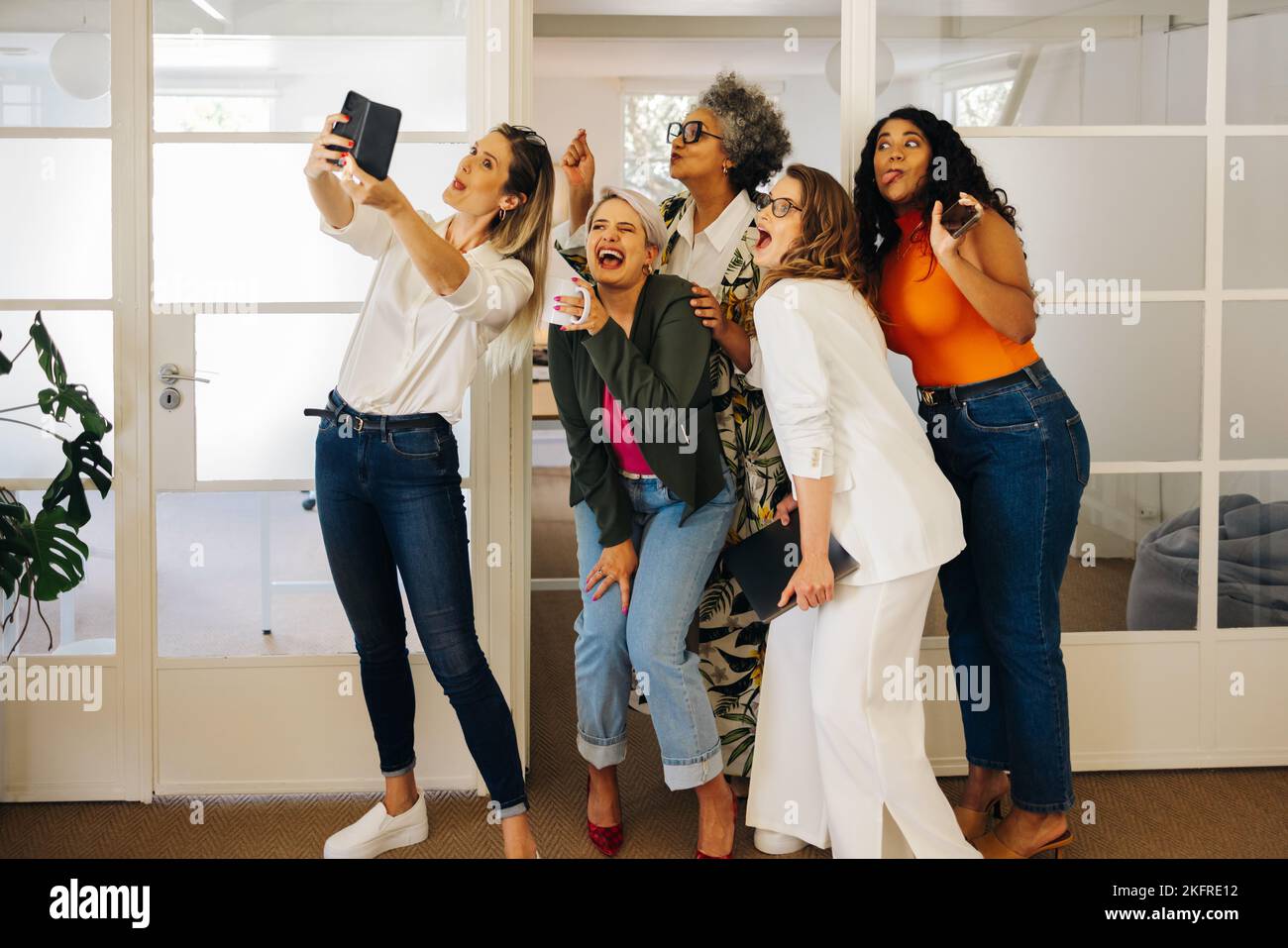 Empresarios diversos haciendo caras divertidas mientras toman un selfie juntos en una oficina creativa. Grupo de empresarios felices celebrando su éxito Foto de stock